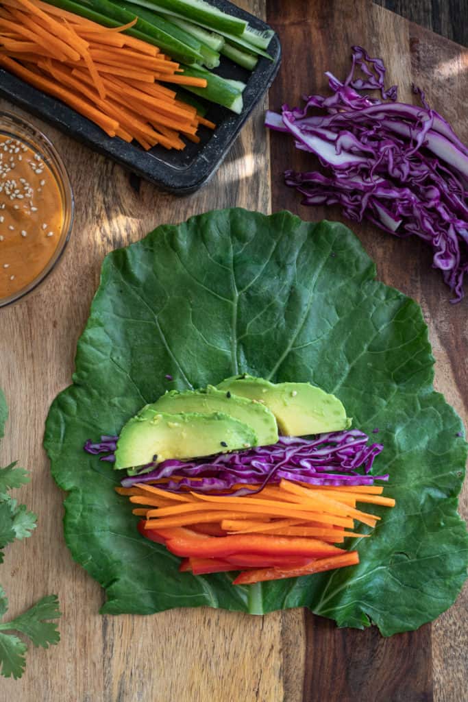 Collard green leaf with carrots peppers and avocado for a wrap.