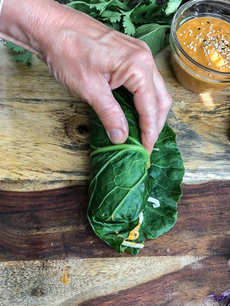 Thai Peanut Salad Roll being wrapped in large collard green.
