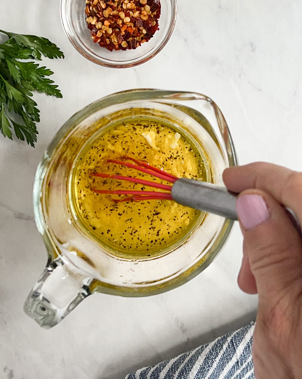 Zesty lemon balsamic dressing being whisked in a large measuring cup.