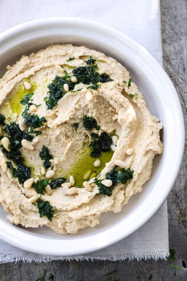 Delicious chickpea hummus in a bowl with a swirl of oil and herbs.