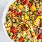 Large bowl of quinoa salad with corn tomatoes and cucumbers.