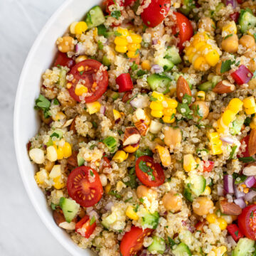Large bowl of quinoa salad with corn tomatoes and cucumbers.