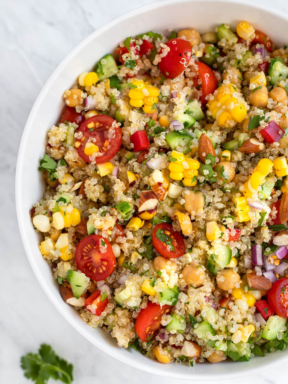 Large bowl of quinoa salad with corn tomatoes and cucumbers.