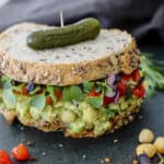 chickpea sandwich on sourdough with leafy greens and hot peppers