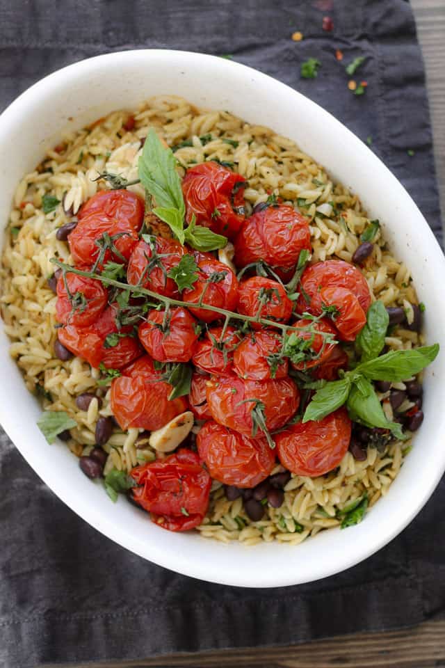 Lemon fennel orzo pasta in a casserole dish topped with a vine of roast tomatoes.