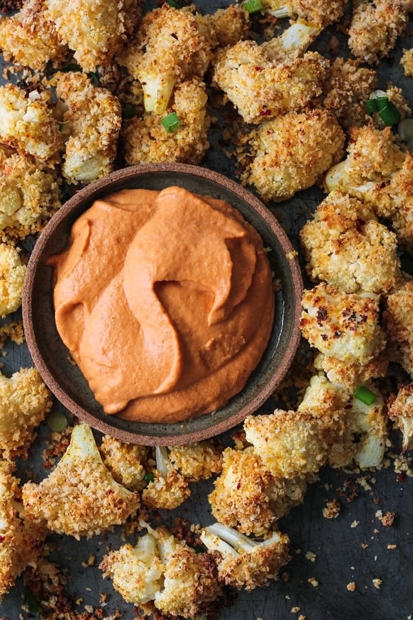 Bowlful of roasted red pepper cashew cream with baked cauliflower wings.
