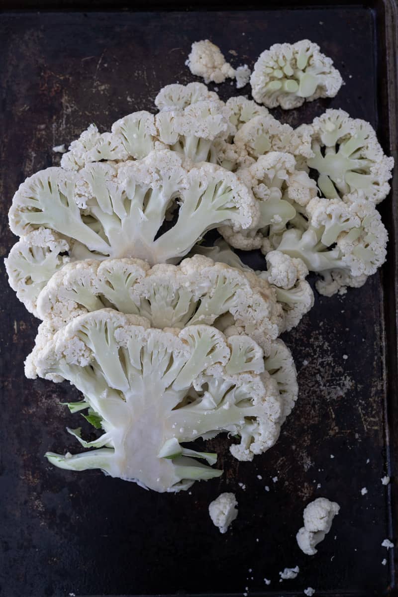 Slices of cauliflower on a roasting pan ready for spicy cauliflower burger.