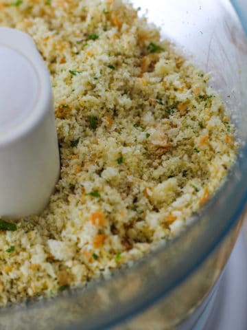 Food processor filled with breadcrumbs and herbs.