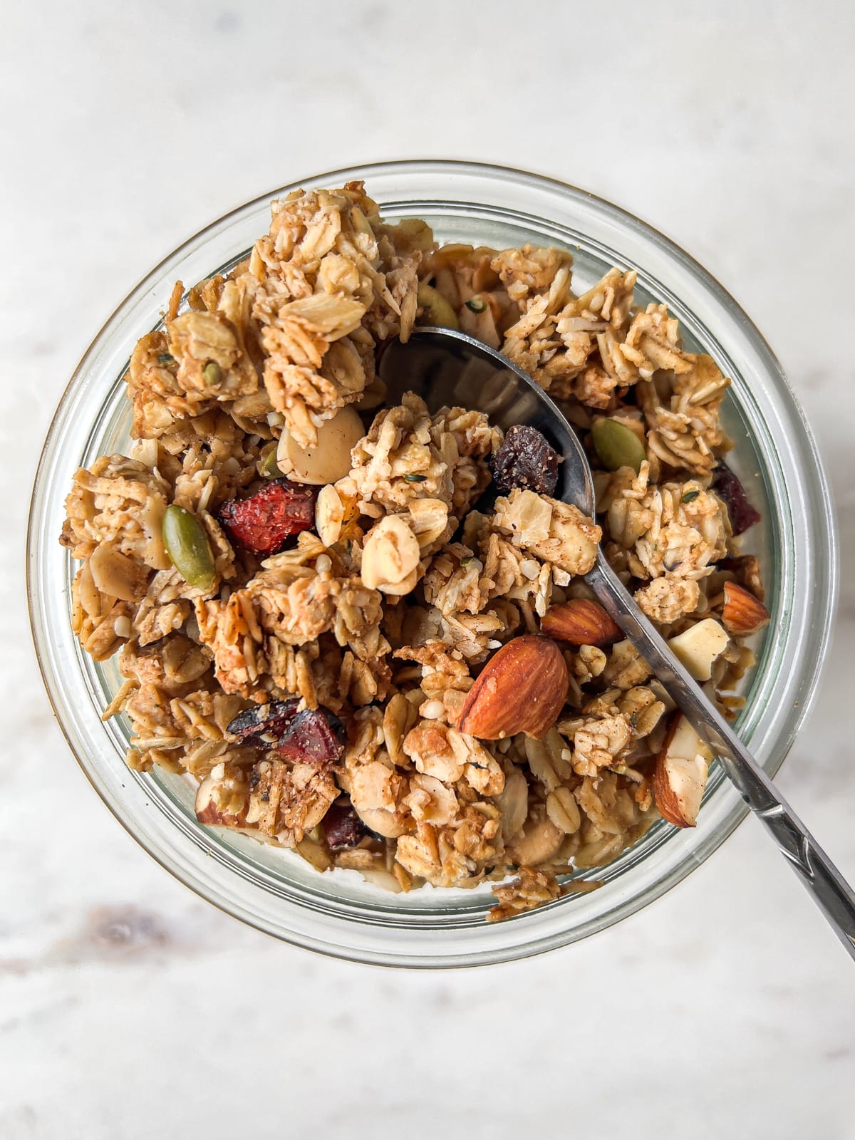 Overhead shot of granola in a jar with a spoonful of granola on top.