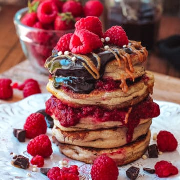 Stack of buttermilk pancakes topped with fresh berries and chocolate ganache.