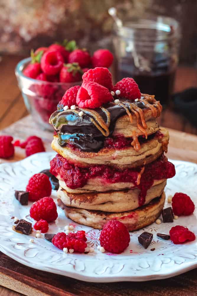 Stack of buttermilk pancakes topped with fresh berries and chocolate ganache.