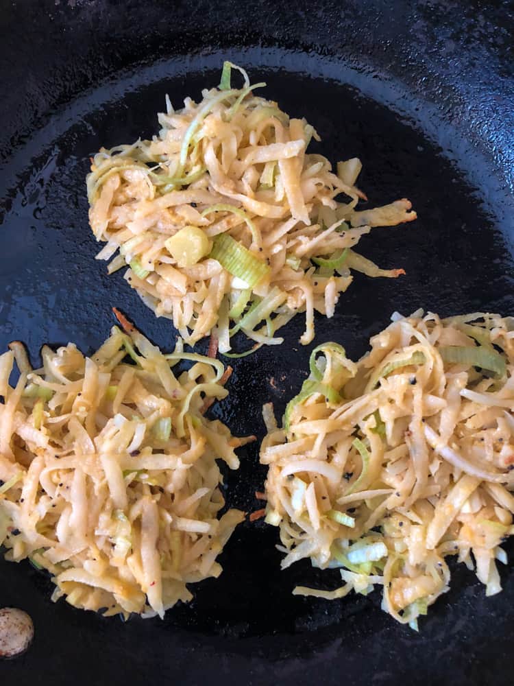 potato-leek pancakes frying in a cast iron pan