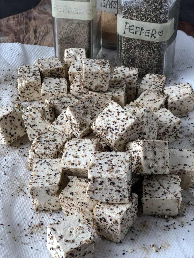 Pile of black pepper crusted tofu cubes on a paper towel.