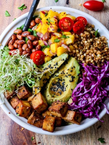 Tofu Buddha bowl with buckwheat, sprouts, beans, and avocado served in a bowl.