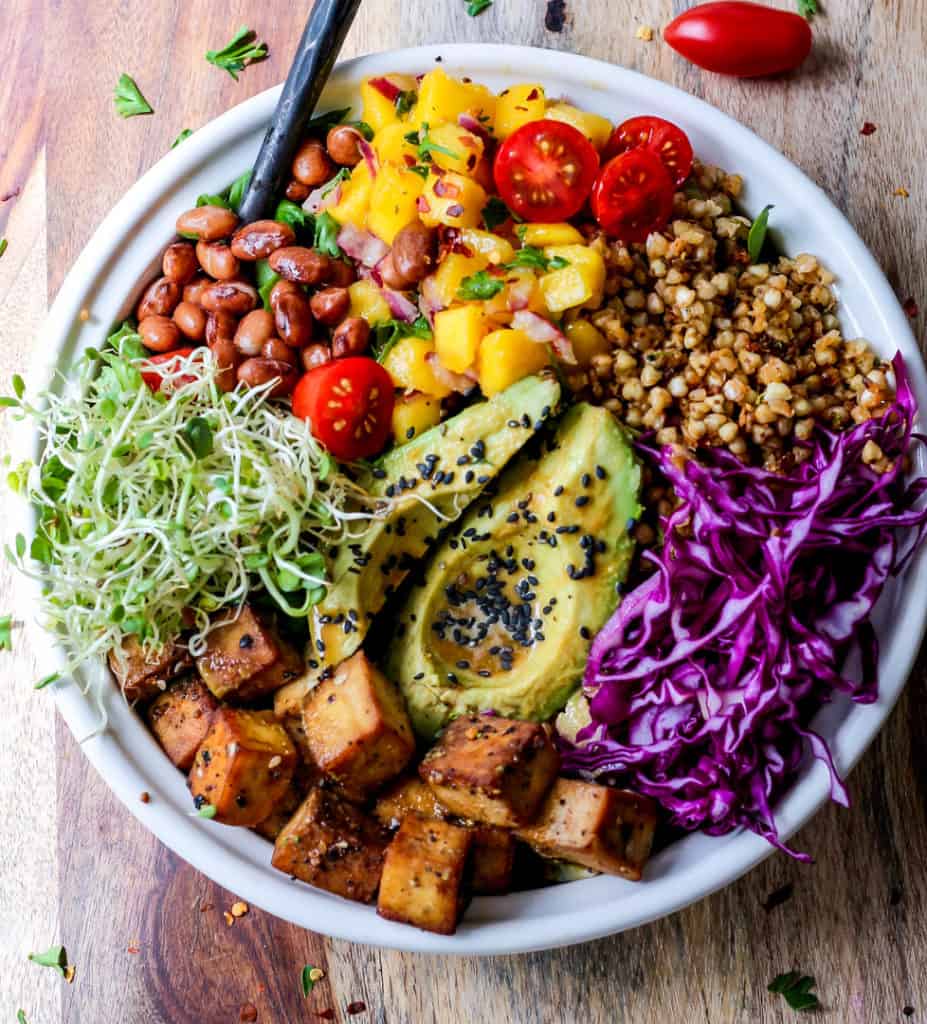 tofu, buckwheat groats, avocado chunks, and mango salsa on a bed of greens with dragon dressing