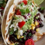 Vegan Corn and black bean tacos with slaw and tomatoes.