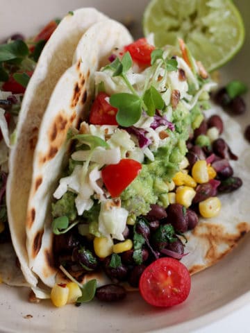 Vegan Corn and black bean tacos with slaw and tomatoes.