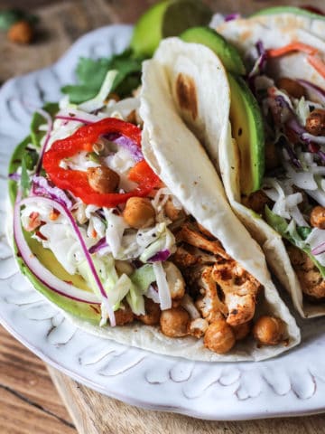 Cauliflower and chickpea taco with creamy slaw in a warm tortilla served on a plate