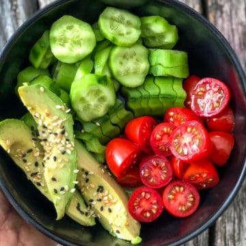 Bowl of cucumbers tomatoes and avocado slices.