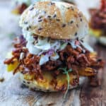 Spicy Pulled Jackfruit and creamy coleslaw served in a seedy slider bun sitting on a cutting board.
