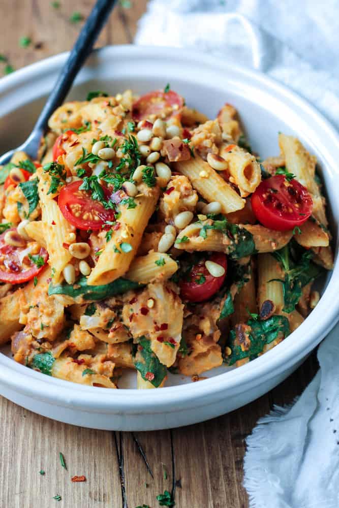 Bowlful of penne pasta tossed with fresh tomato, spinach, cauliflower and olive hummus sauce.