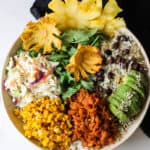 Jackfruit Buddha bowl with rice, avocado, beans, slaw and corn in a bowl.