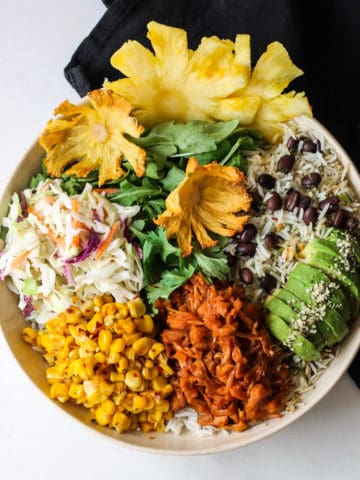 Jackfruit Buddha bowl with rice, avocado, beans, slaw and corn in a bowl.