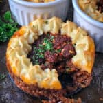 Vegan Shepherd's pie filling piped with mashed potatoes baked in individual mini pots.