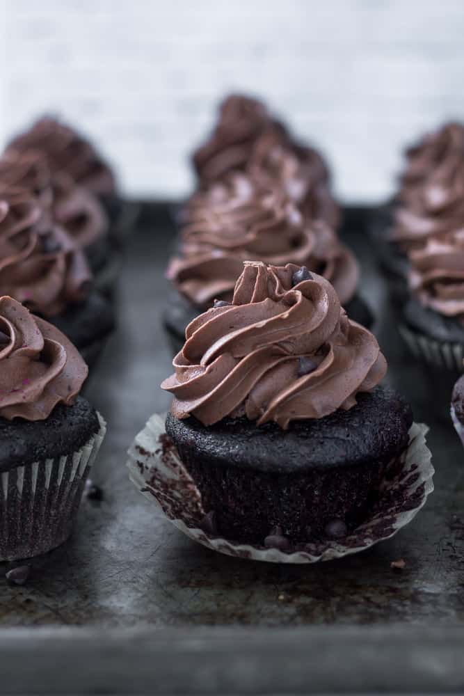 Gorgeous vegan chocolate cupcakes with a large swirl of chocolate icing sitting on a serving tray.