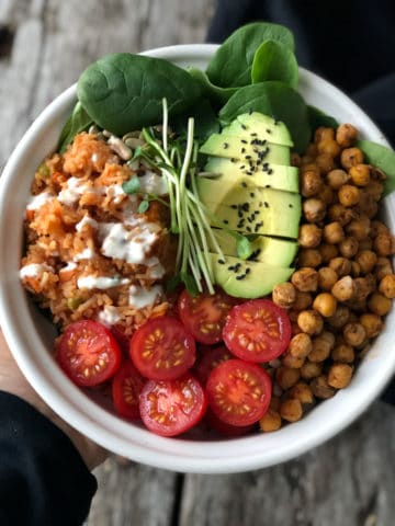 Mexican rice and chorizo chickpea bowl with tomatoes and half an avocado in a bowl.