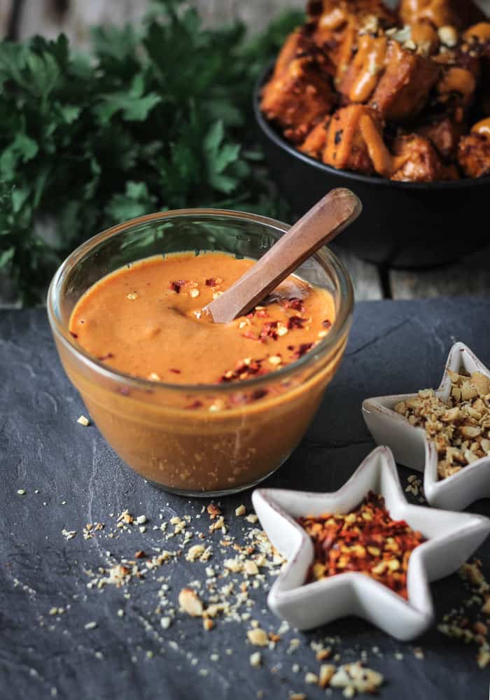 Spicy vegan peanut sauce in a bowl sitting in front of a bowl of satay peanut tofu!