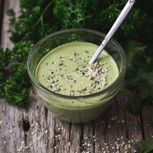 Bowl of creamy green chimichurri sauce on a serving board.