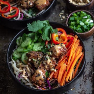 Peanut sauce noodle bowl with carrots and tofu on a platter.