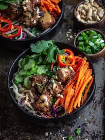 Peanut sauce noodle bowl with carrots and tofu on a platter.