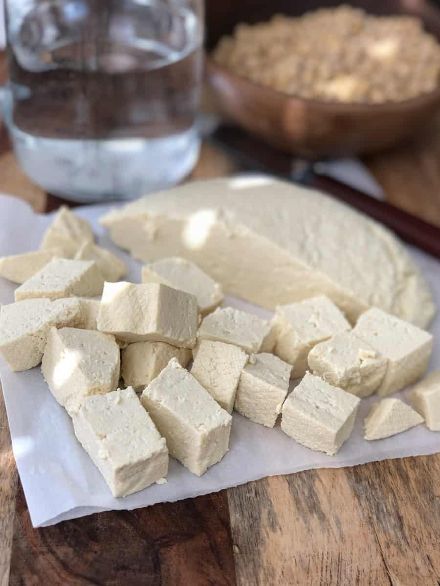 Fresh tofu cut into cubes on cutting board.