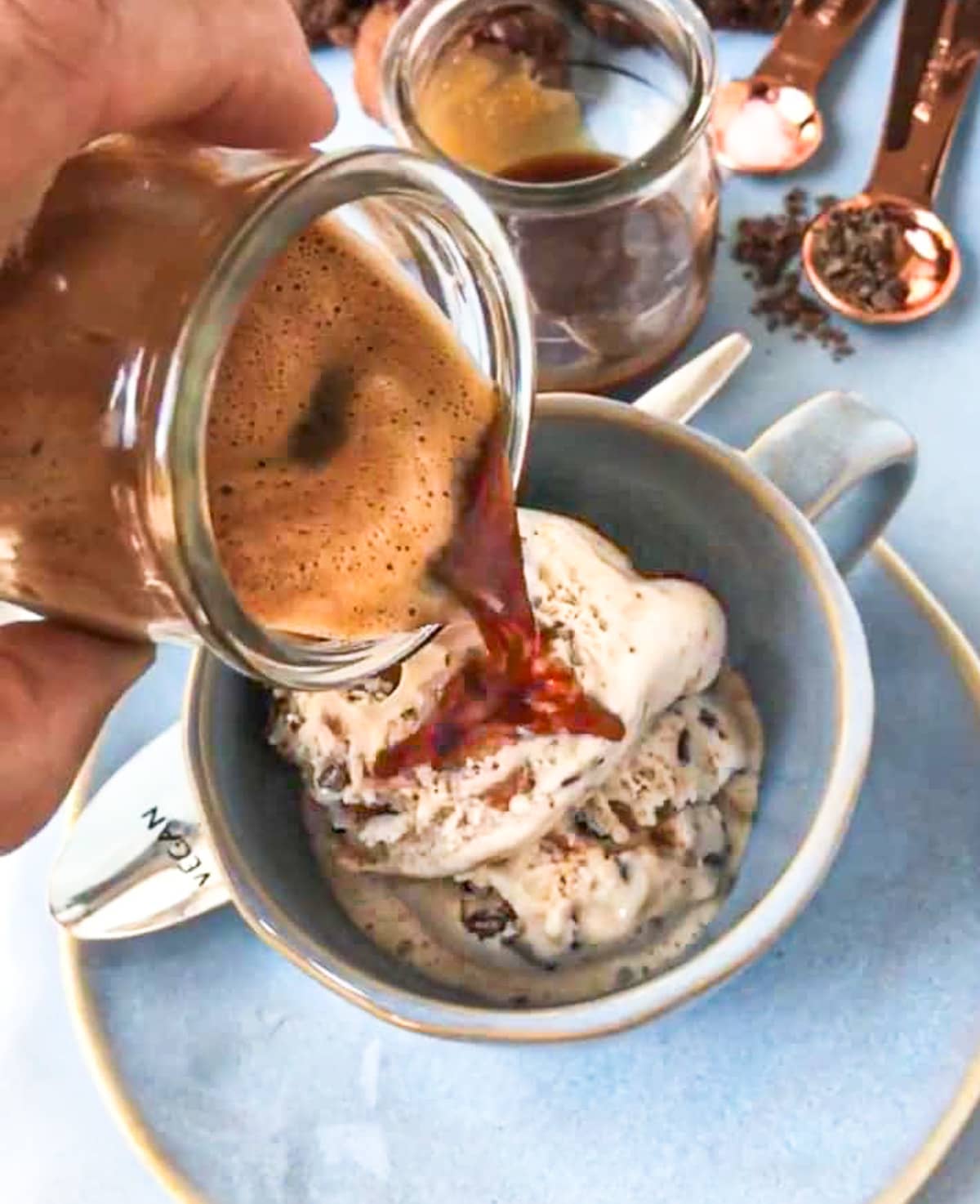 Espresso being poured over ice cream in a mug.