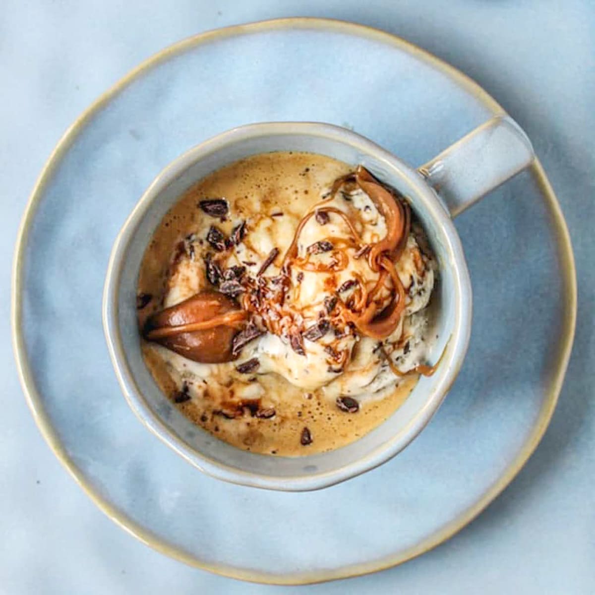 Cup of espresso with vanilla ice cream topped with caramel and chocolate curls.