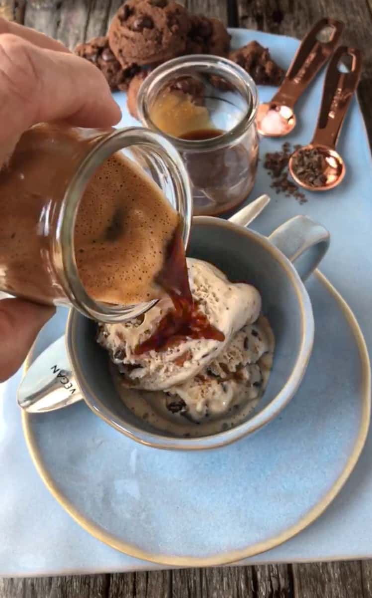 Espresso being poured over a scoop of ice cream in a coffee cup.