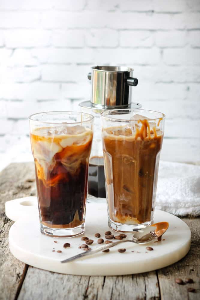 Splash of iced coffee in tall glass and coffee beans. Stock Photo