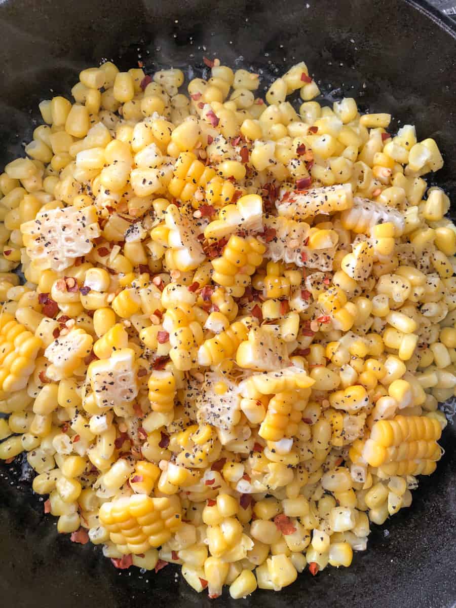 Large pan of grilled corn niblets topped with spices.