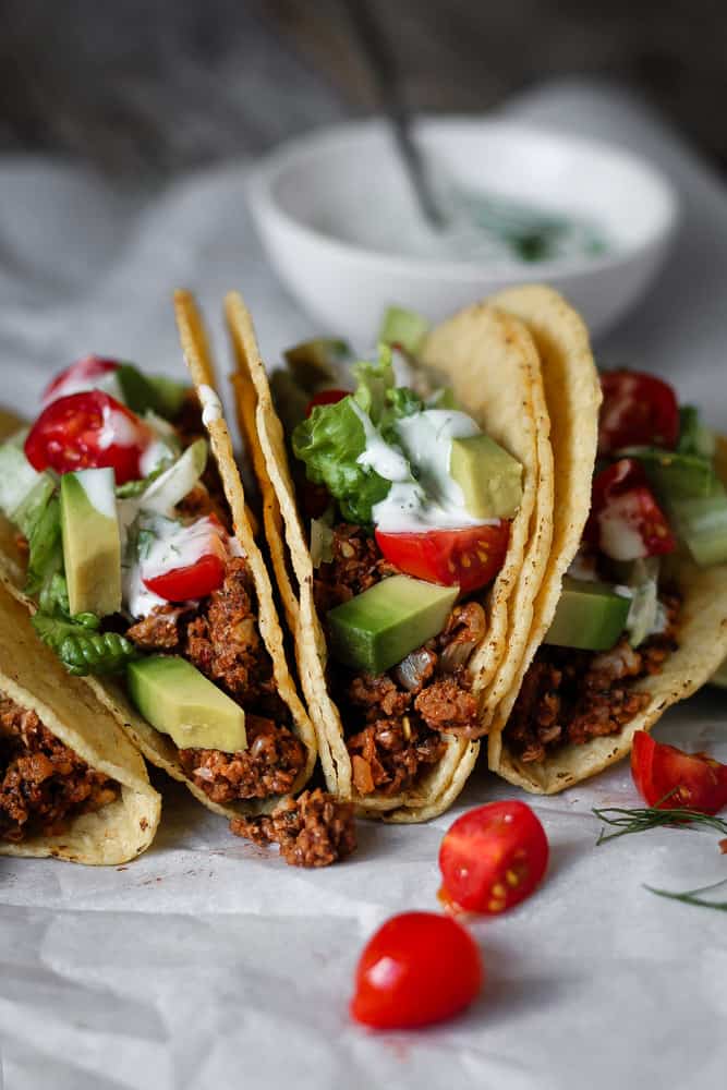 spicy vegan tofu meat tacos topped with tomatoes avocado and tangy sauce