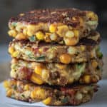 Stack of vegan corn fritters on a serving board.