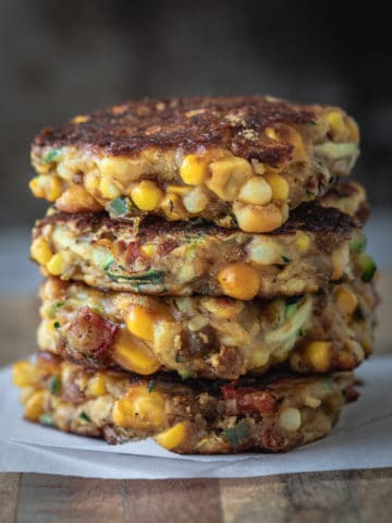 Stack of vegan corn fritters on a serving board.