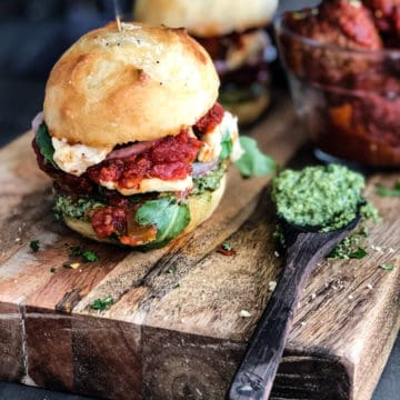 vegan meatball buns on a cutting board with pesto and marinara sauce