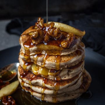 stack of vegan pancakes with syrup drizzle and bacon walnut crumbles