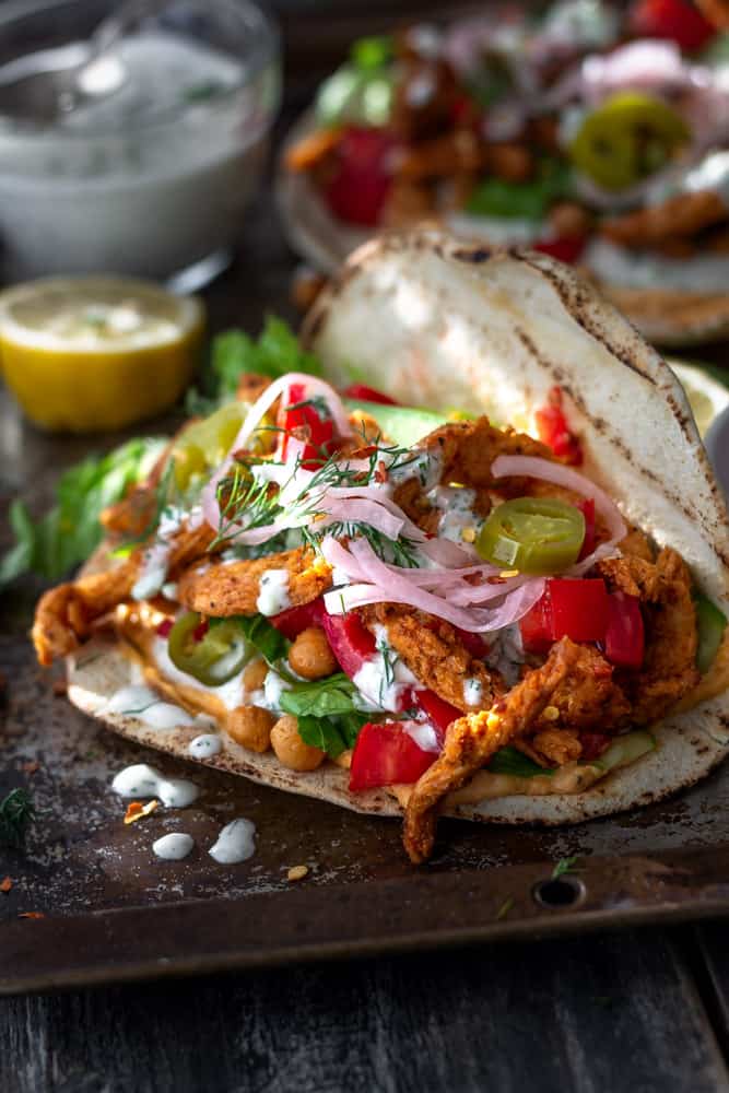 Vegan soy curl shawarma in a pita pocket with tomatoes and pickled onions.