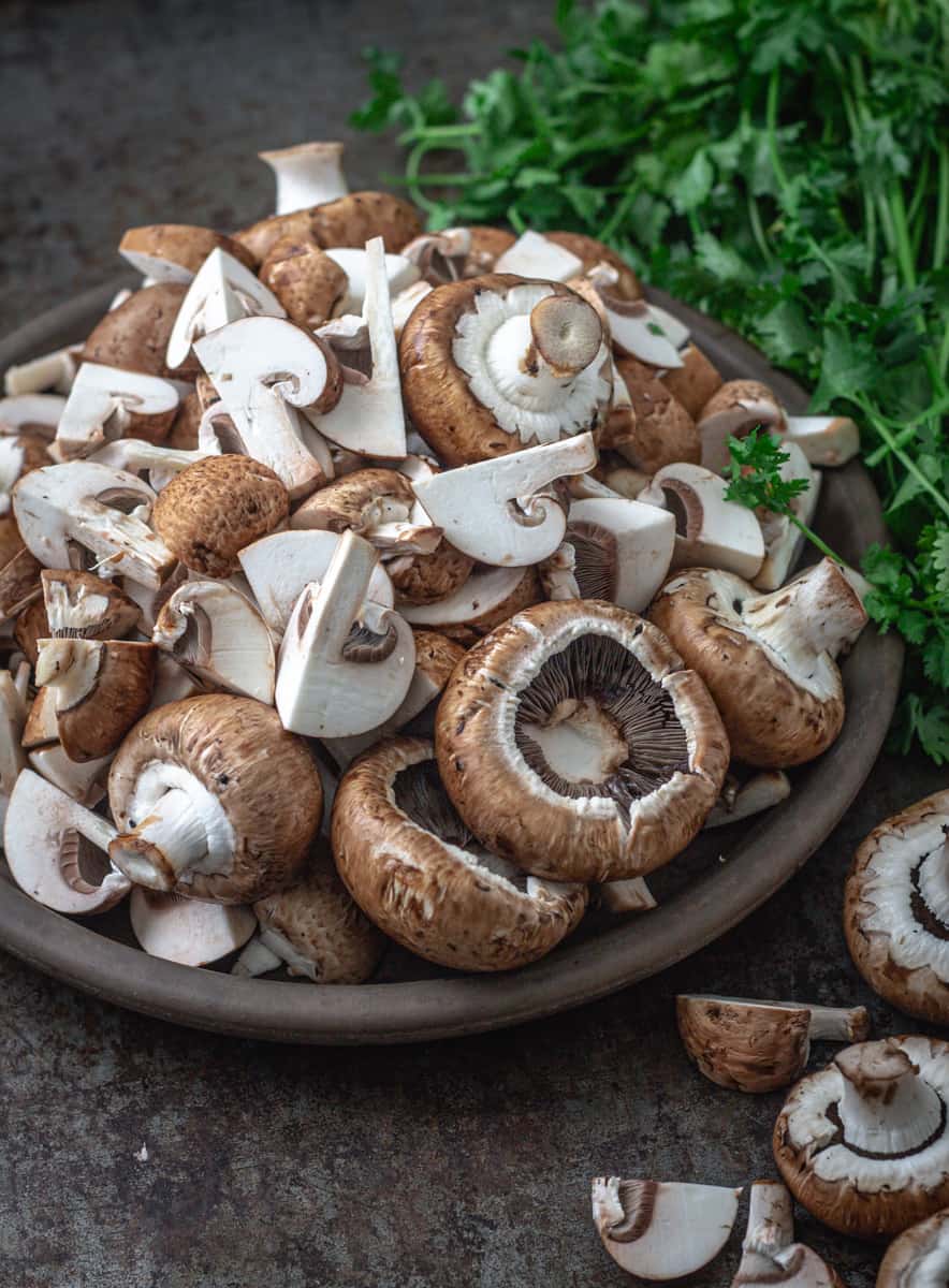 Bowl of whole and cut mushrooms for vegan sausage roll filling.