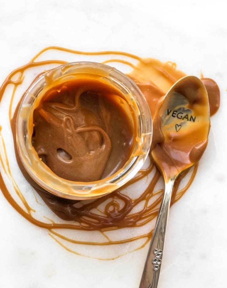 Overhead shot of pot of vegan salted caramel sauce and spoon.