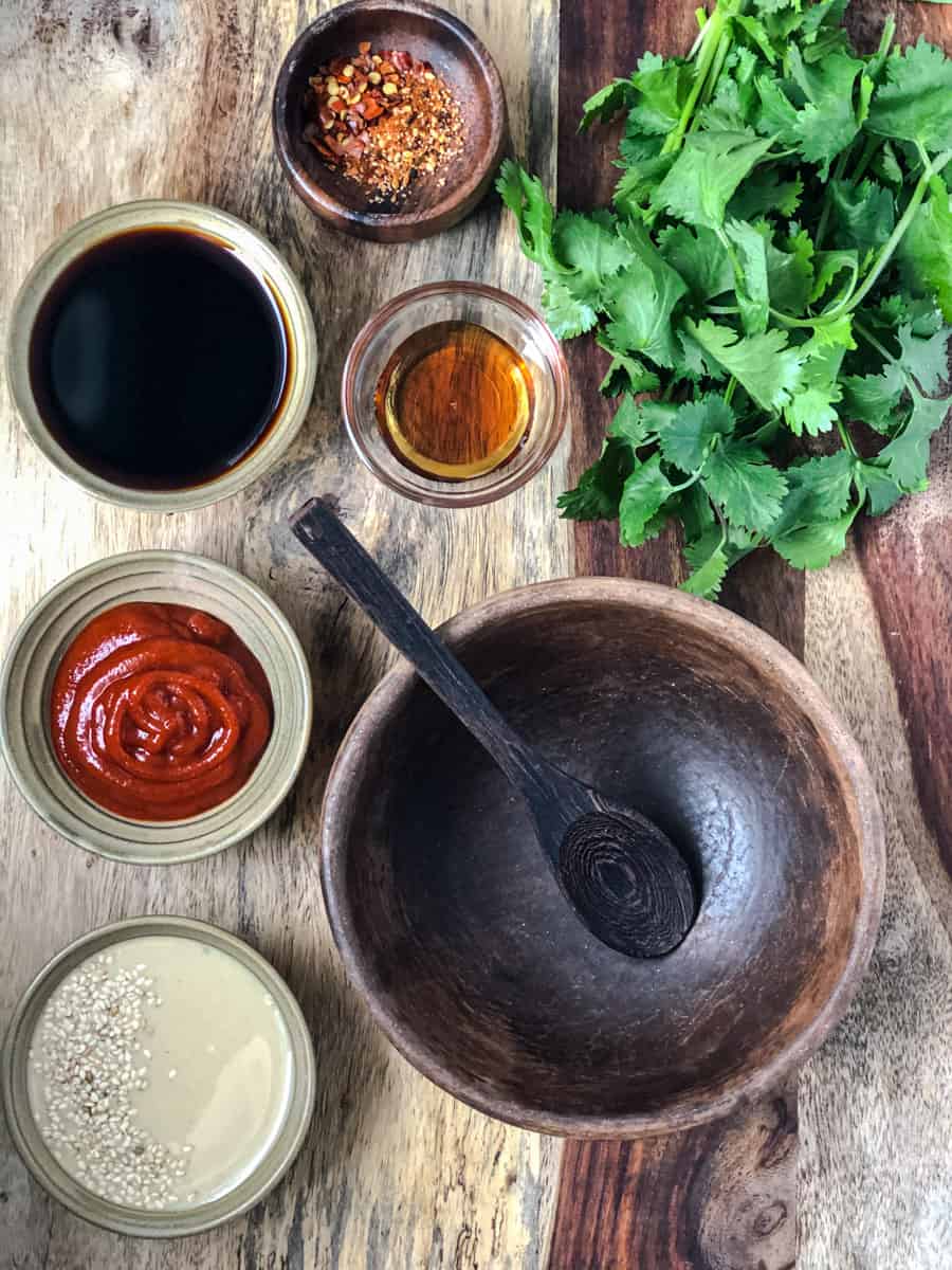 Small bowls of ingredients for dan dan sauce on a serving board.