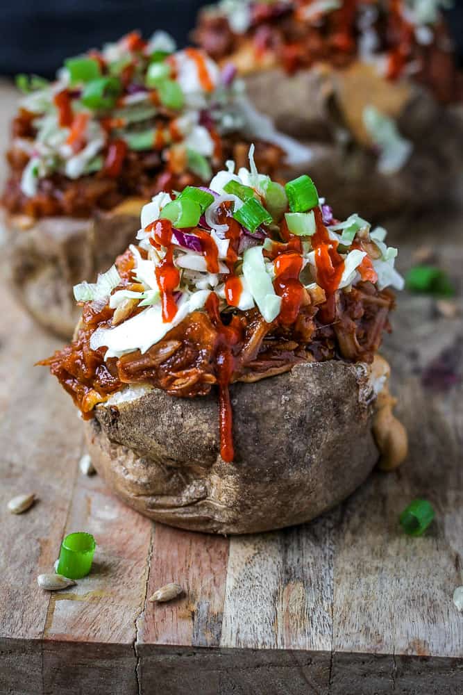 Saucy BBQ jackfruit in a baked potatoes topped with sloppy slaw and cashew cream.